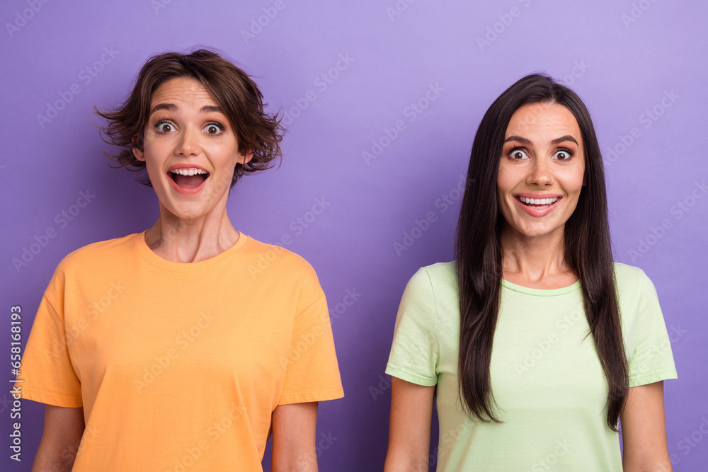 Photo of impressed funky girls dressed t-shirts big eyes open mouth isolated purple color background Photo of impressed funky girls dressed t-shirts big eyes open mouth isolated purple color background