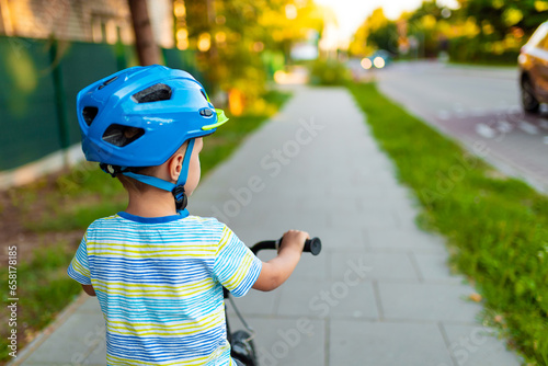 Toddler boy in helmet after bike  ride. Sport lifistyle kids. Child active outdoor. Bicycle on the green grass. photo