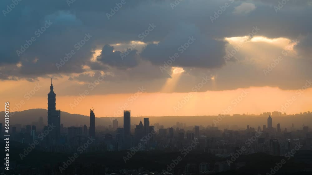 At dusk, the sun breaks through the clouds and shines on Taipei City. Silhouettes of city buildings. Orange sky and dark clouds. At dusk, the sun breaks through the clouds and shines on Taipei City. Silhouettes of city buildings. Orange sky and dark clouds.