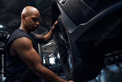 African American auto-mechanic changing seasonal tires and doing tire balancing