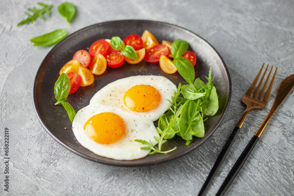 Fried eggs and Caprese salad with tomatoes, mozzarella cheese and basil leaves in a plate. Fried eggs and Caprese salad with tomatoes, mozzarella cheese and basil leaves in a plate.