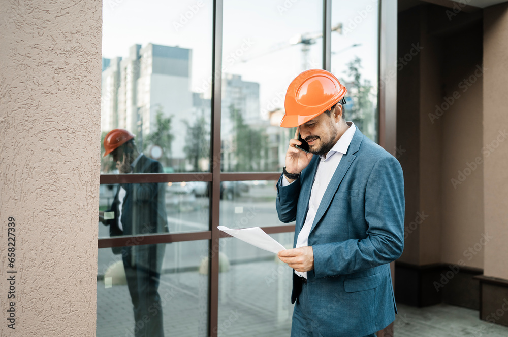 Smiling engineer talking on smart phone in front of building Smiling engineer talking on smart phone in front of building