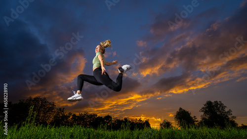 Athlete jumping with sky in background at dusk photo