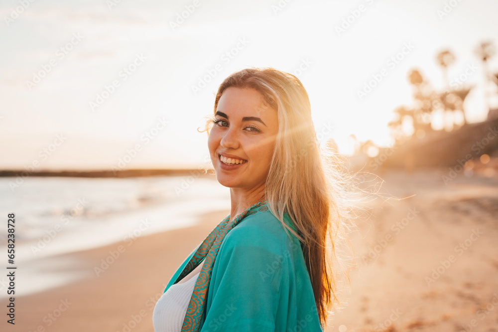Portrait of one happy beautiful woman on the sand of the beach enjoying and having fun at the sunset of the day. Looking at the camera smiling.. Portrait of one happy beautiful woman on the sand of the beach enjoying and having fun at the sunset of the day. Looking at the camera smiling..