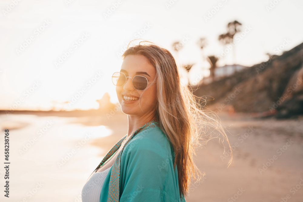 Portrait of one happy beautiful woman on the sand of the beach enjoying and having fun at the sunset of the day. Looking at the camera smiling.. Portrait of one happy beautiful woman on the sand of the beach enjoying and having fun at the sunset of the day. Looking at the camera smiling..