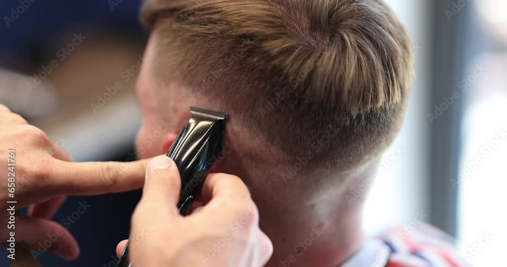 Barber cuts man hair with hair clipper in barbershop. Men hairstyle and haircut in salon Barber cuts man hair with hair clipper in barbershop. Men hairstyle and haircut in salon