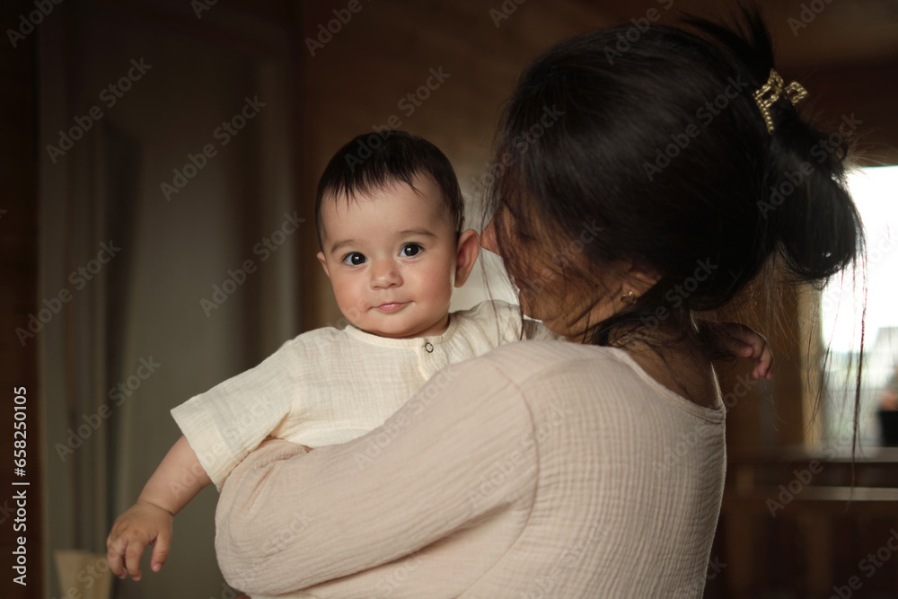 Maternal Bliss: An elated mother cherishes quality time with her baby, enveloped in the dappled daylight of their rustic sanctuary Maternal Bliss: An elated mother cherishes quality time with her baby, enveloped in the dappled daylight of their rustic sanctuary