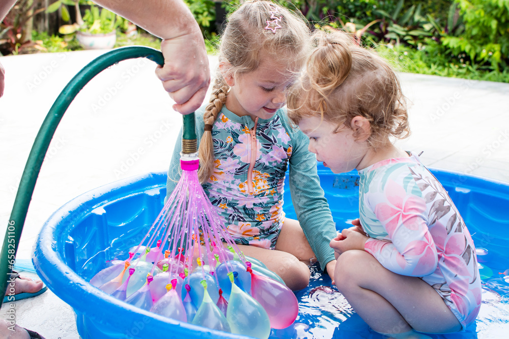 Kids playing in a kiddie pool with water balloons. Summer activities