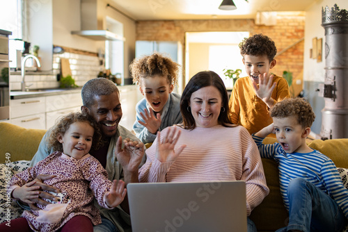 Young mixed family talking to somebody on a video call on the couch at home photo