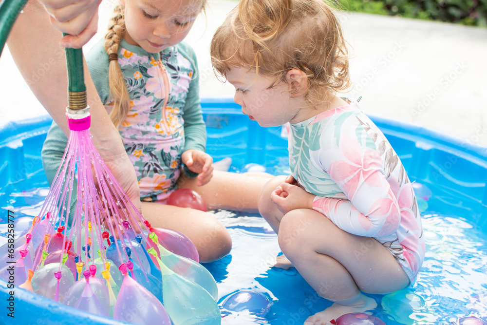 Kids playing in a kiddie pool with water balloons. Summer activities