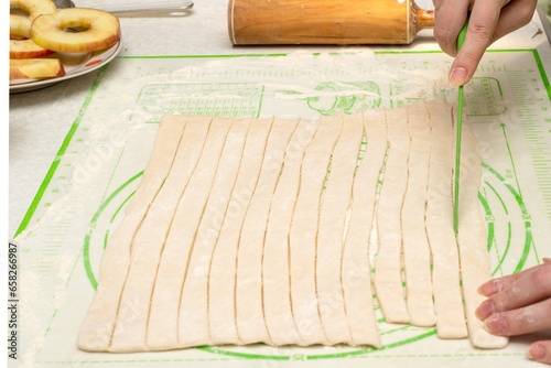 Cutting puff pastry into strips with a knife.