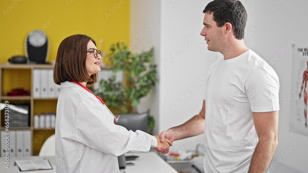 Doctor and patient shaking hands smiling at the clinic