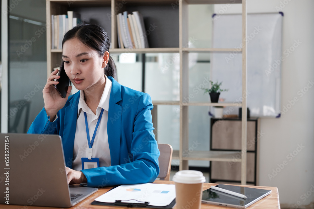 Business woman at work talking on phone and taking notes, sitting at her working place in office Business woman at work talking on phone and taking notes, sitting at her working place in office
