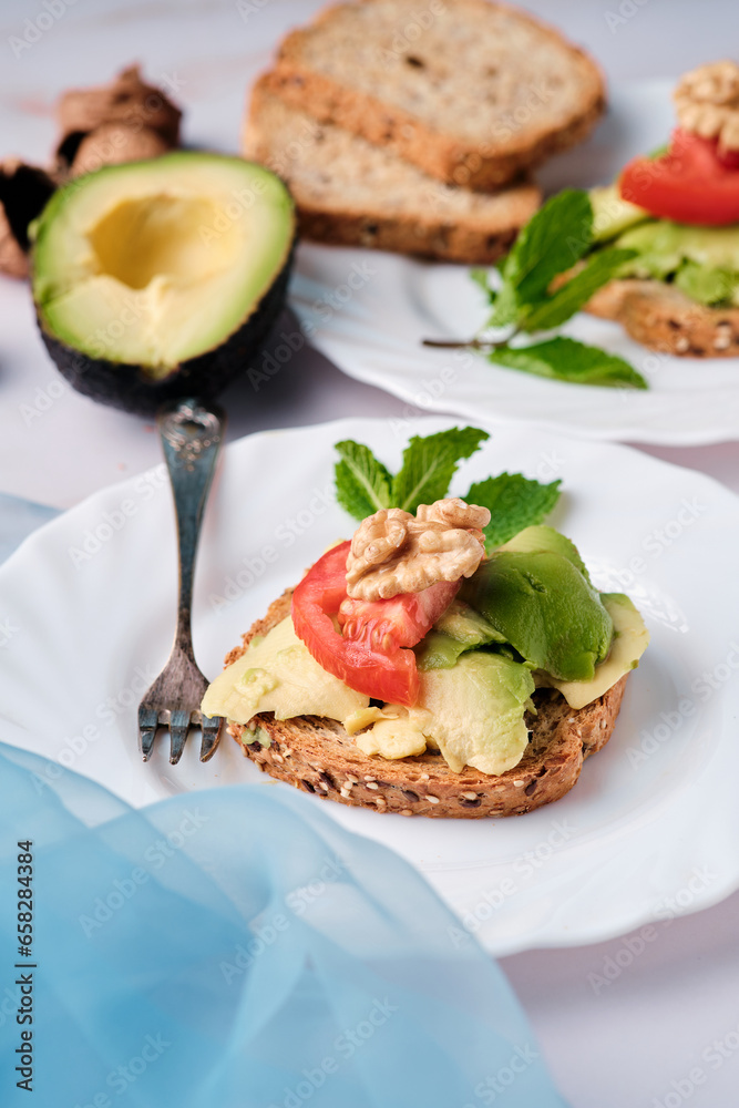 toasted bread with avocado paste and fresh tomato. Avocado mixed with lemon juice is spread on the bread. healthy food concept, vegan, vegetarian