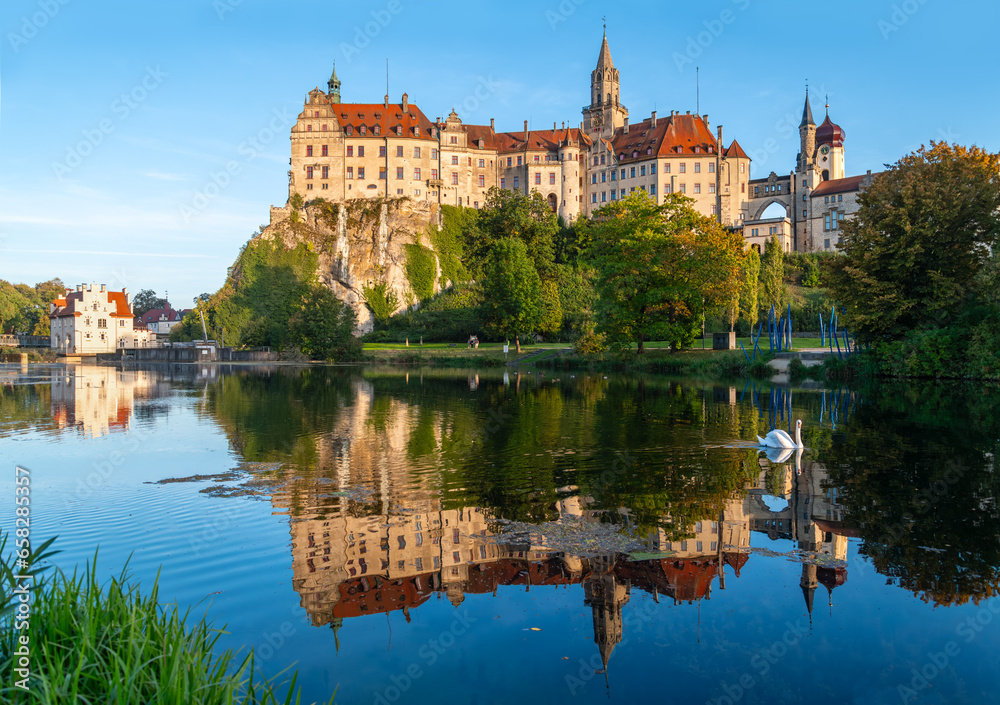 Sigmaringen castle is a historic monument and landmark in southern Germany on a rock in old town centre. Late summer evening panorma with reflection in river Danuve and water fowl. Tourist attraction.