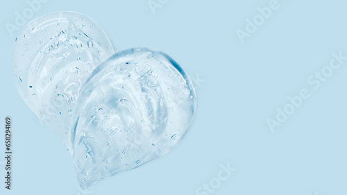 Drops and smears of a transparent gel or serum on a blue background. Banner with empty space for advertising. © Marina Red
