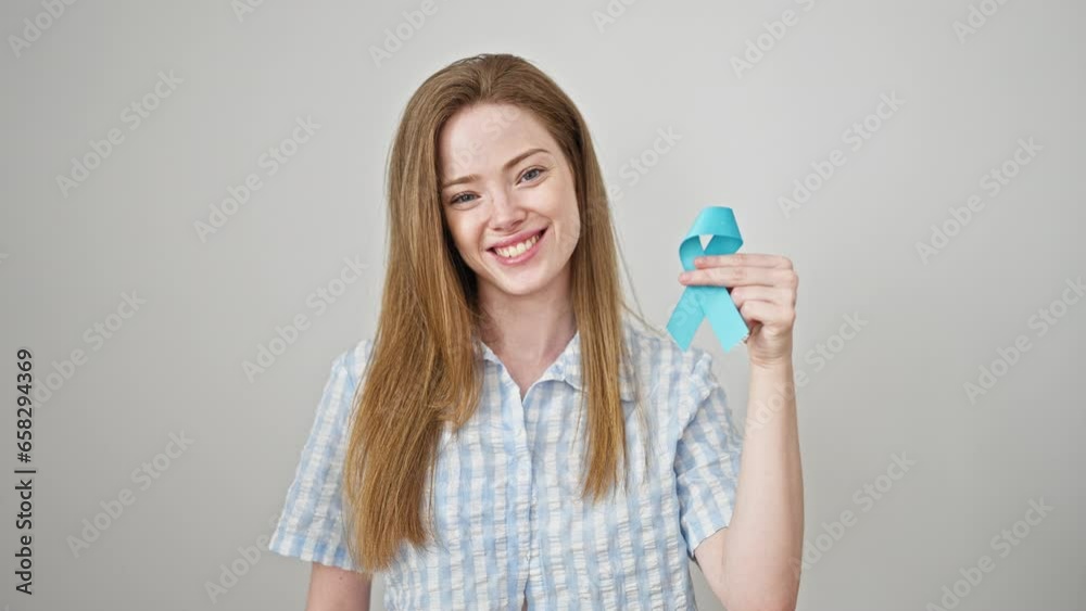 Young blonde woman holding light blue ribbon smiling over isolated white background Young blonde woman holding light blue ribbon smiling over isolated white background