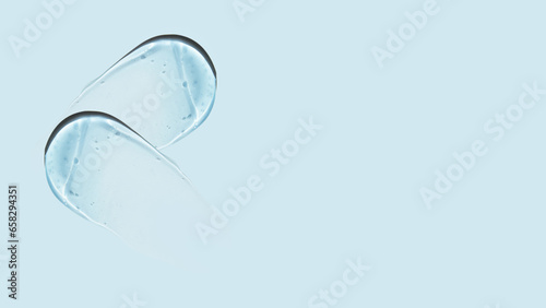 Drops and smears of a transparent gel or serum on a blue background. Banner with empty space for advertising.