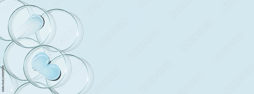 Petri dishes and drops and ointments of transparent gel or serum on a blue background. Banner with empty space for advertising. Petri dishes and drops and ointments of transparent gel or serum on a blue background. Banner with empty space for advertising.