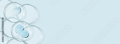 Petri dishes and drops and ointments of transparent gel or serum on a blue background. Banner with empty space for advertising.