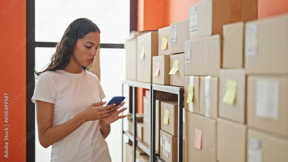 African american woman ecommerce business worker checking packages using smartphone at office