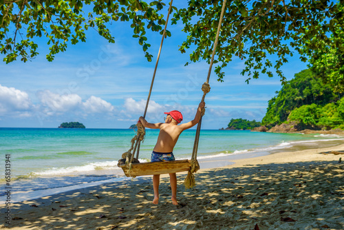 A boy swings on Loneli beach in Koh Chang, Thailand  photo