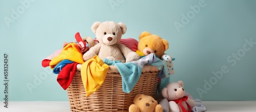 Children s clothes and toy in a laundry basket on a light background photo