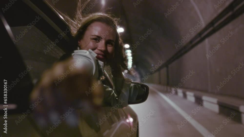 Portrait of a beautiful girl hang out of car window on sunny road trip ...