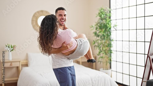 Man and woman couple holding girlfriend on arms turning at bedroom