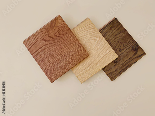 Sample samples of hardwood or laminate flooring with different types of wood textures isolated on a beige background. A variety of shades of wooden flooring material. Samples of laminated boards
