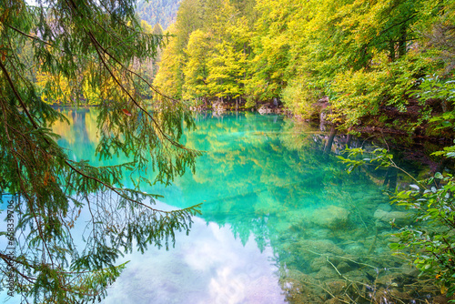 Laghi di Fusine inferior lake  Tarvisio  Italy. Amazing autumn landscape  crystal clear water with reflection and colored forest surrounded by Mangart mountain range  outdoor travel background