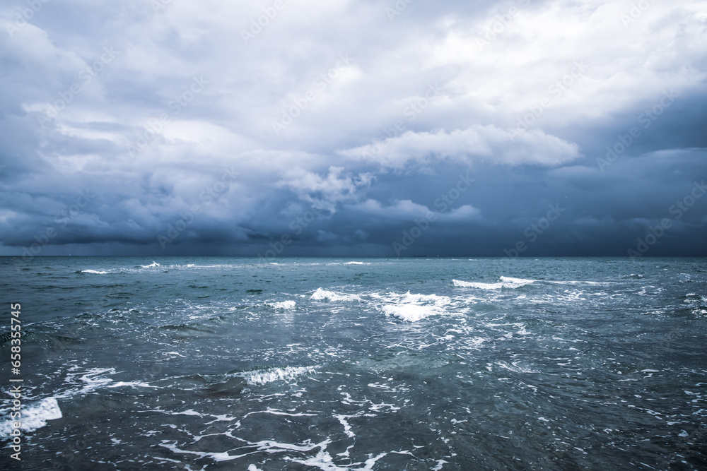 Dramatic seascape in dark colors. Dark sky with clouds over the stormy sea.