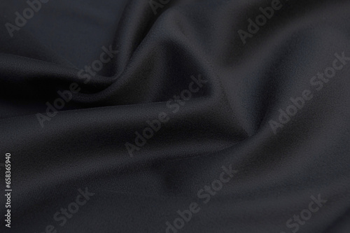 Close-up texture of natural gray or black fabric or cloth in same color. Fabric texture of natural wool textile material. Black canvas background.