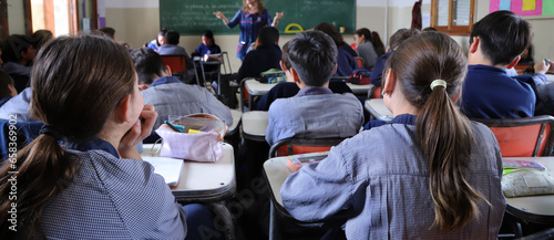 Group of students in a classroom with a teacher explaining a topic.  Boys at their desks dressed in uniform. Education. Children learning at school. photo