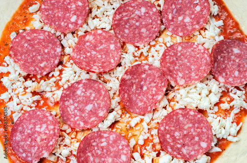 pizza preparation process, sliced salami sausage, close-up