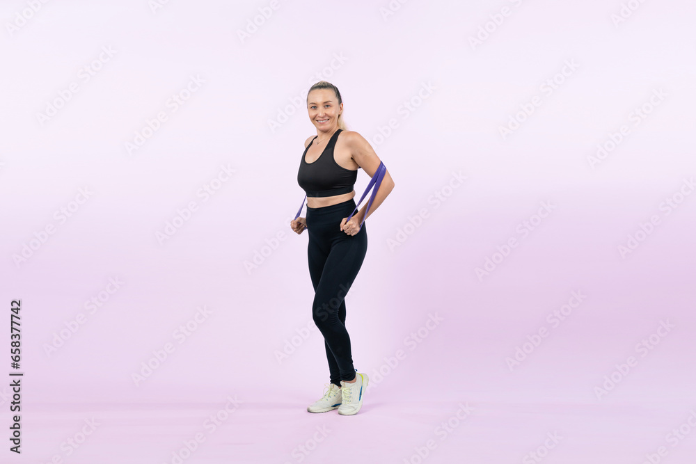 Full body length shot athletic and sporty senior woman with fitness resistance band on isolated background. Healthy active physique and body care lifestyle after retirement. Clout - obrazy, fototapety, plakaty 