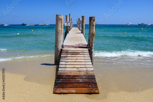 Fototapeta Naklejka Na Ścianę i Meble -  Wooden pier and crystal clear blue water of legendary Pampelonne beach near Saint-Tropez, summer vacation on French Riviera, France, text translation: it's dangerous not to dive from pier.