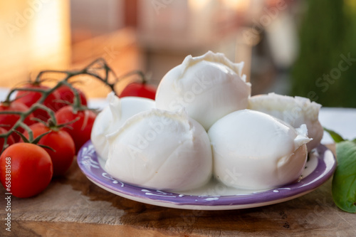 White balls of Italian soft cheese Mozzarella di Bufala Campana served with fresh green basil and red sicilian tomatoes