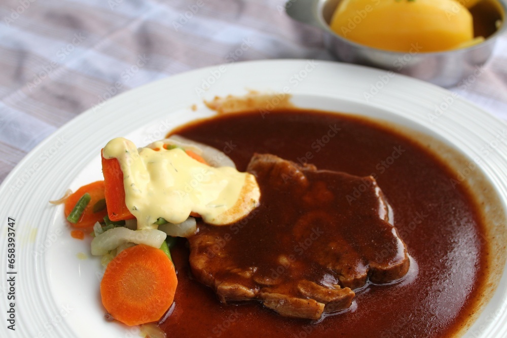 Schweinebraten mit einer dunklen Soße, Gemüse, Bechamelsauce, Salzkartoffeln, Spätzle. Eine bayrische Spezialität. Schweinebraten mit einer dunklen Soße, Gemüse, Bechamelsauce, Salzkartoffeln, Spätzle. Eine bayrische Spezialität.