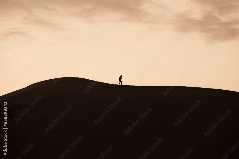 Person walking on the top of a dune during a sunset in Ica Peru