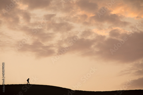 Person walking on the top of a dune during a sunset in Ica Peru