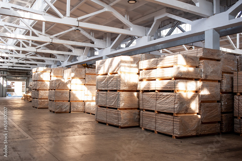 Industrial warehouse with stacked wooden planks and finished wood products ready for distribution photo