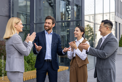 Canvas Print Business people outside office building applauding and congratulating colleague boss with promotion and good results achievement, four people, women and men on work break outdoors