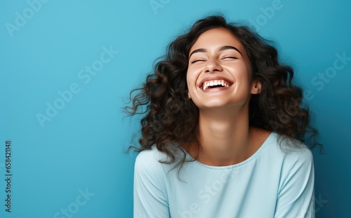 Photo of young female smiling and laughing on bright blue background © steffenak