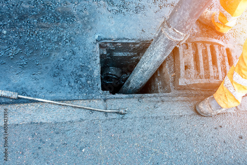 Builder cleaning blocked road gully with shovel and vacuum excavator
