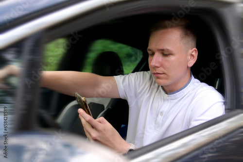 Young careless driver use mobile phone while driving a car photo