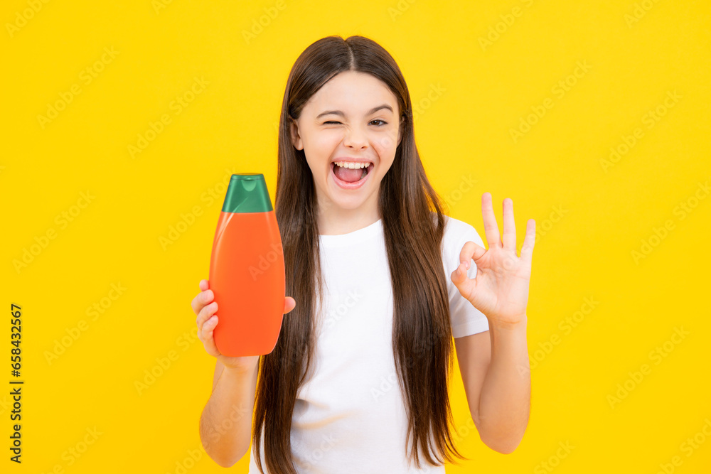 Teenager child girl showing bottle shampoo conditioners or shower gel. Hair cosmetic product. Bottle for advertising mock up copy space. Excited teenager, glad amazed and overjoyed emotions. Teenager child girl showing bottle shampoo conditioners or shower gel. Hair cosmetic product. Bottle for advertising mock up copy space. Excited teenager, glad amazed and overjoyed emotions.
