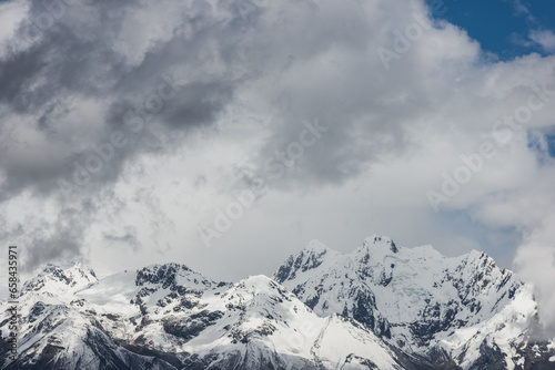 Landscape of snow-capped mountains and clouds above them. Travel concept