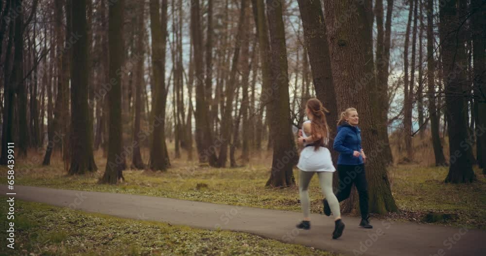 Fit female friends jogging on street in garden