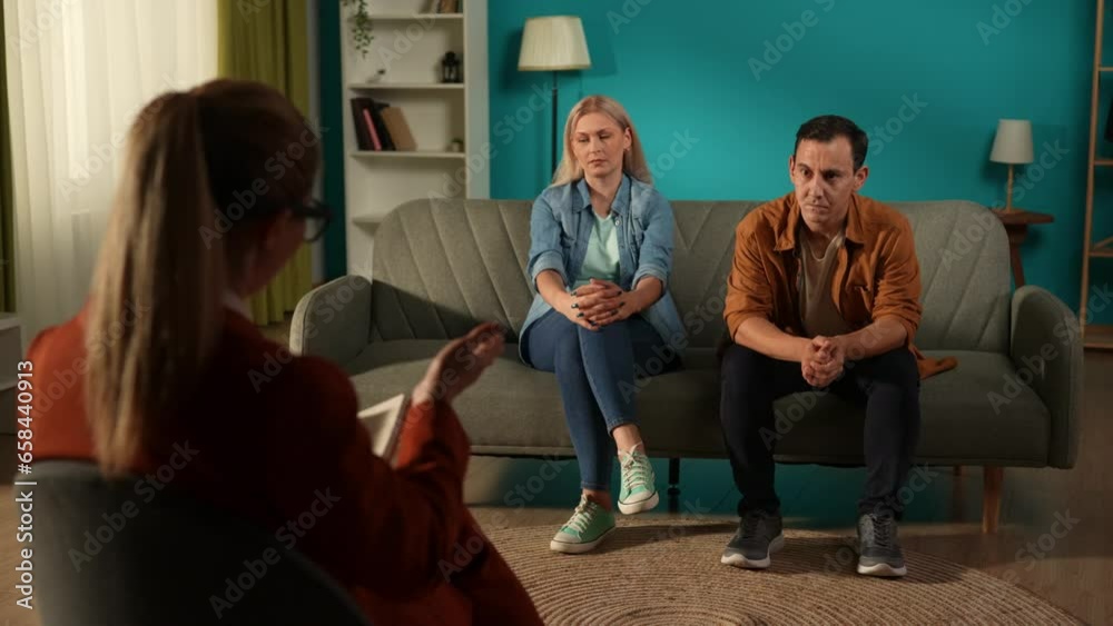 A man and a woman sitting on a couch in front of an expert in a joint psychotherapy session. Back view of a female therapist helping a couple come to an understanding. A man and a woman sitting on a couch in front of an expert in a joint psychotherapy session. Back view of a female therapist helping a couple come to an understanding.